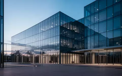 Ein modernes, minimalistisches Bürogebäude bei Dämmerung, das die blaue Atmosphäre des Himmels reflektiert. - Foto: über boerse-global.de