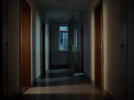 Ein ruhiger Flur in einem Wohngebäude bei Nacht mit einer schlichten Holztür. - Foto: über boerse-global.de