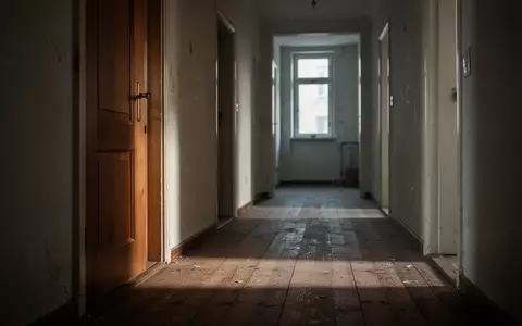 Ein leerer, schattiger Flur in einem Berliner Wohnhaus mit Holzdielen und einer geschlossenen Tür. - Foto: über boerse-global.de