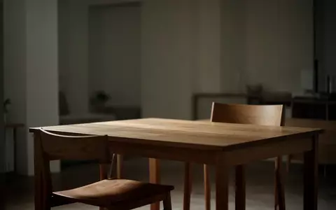 Ein ruhiger, minimalistisch eingerichteter Raum mit einem leeren Stuhl an einem Holztisch in gedimmtem Licht. - Foto: über boerse-global.de