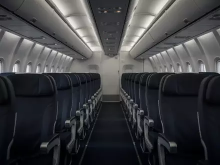 Leere Flugzeugkabine mit Sitzreihen bei gedimmtem Licht während eines Langstreckenflugs. - Foto: über boerse-global.de