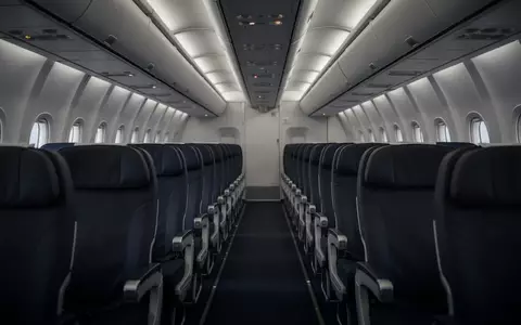 Leere Flugzeugkabine mit Sitzreihen bei gedimmtem Licht während eines Langstreckenflugs. - Foto: über boerse-global.de