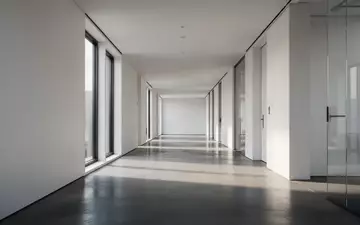 Ein minimalistischer, leerer Büroflur in einem modernen Gebäude mit natürlichem Lichteinfall. - Foto: über boerse-global.de