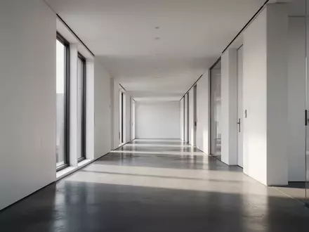 Ein minimalistischer, leerer Büroflur in einem modernen Gebäude mit natürlichem Lichteinfall. - Foto: über boerse-global.de
