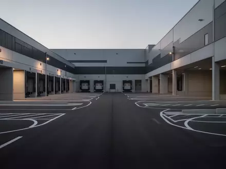 Ein leeres, modernes Logistikgelände mit Laderampen und Asphaltflächen bei Dämmerung. - Foto: über boerse-global.de