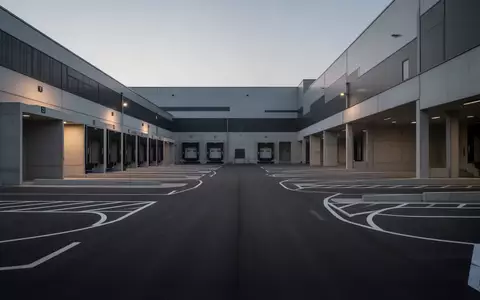 Ein leeres, modernes Logistikgelände mit Laderampen und Asphaltflächen bei Dämmerung. - Foto: über boerse-global.de