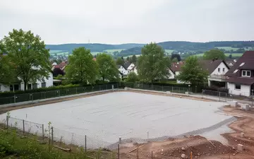 Ein unberührtes Baugrundstück in einem Wohngebiet, das für zukünftige Immobilienprojekte vorbereitet wurde. - Foto: über boerse-global.de