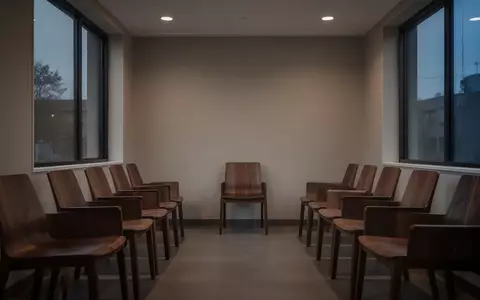 Ein leerer, minimalistischer Wartebereich einer Arztpraxis bei Dämmerlicht mit leeren Stühlen und gedämpftem Licht. - Foto: über boerse-global.de