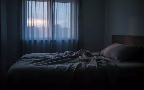 Ein ungemachtes Bett in einem schlafzimmerähnlichen Raum bei morgendlichem Dämmerlicht, das eine ruhige und nachdenkliche Atmosphäre ausstrahlt. - Foto: über boerse-global.de