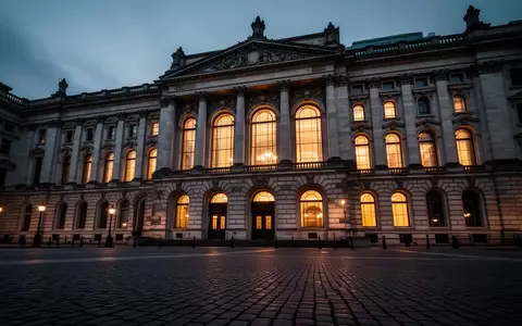 Die nächtliche Fassade eines historischen Regierungsgebäudes mit beleuchteten Fenstern und einem leeren Vorplatz. - Foto: über boerse-global.de