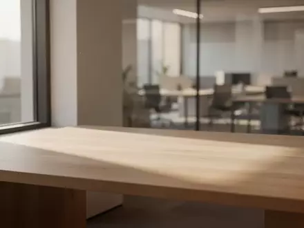 Ein minimalistischer, lichtdurchfluteter Arbeitsplatz mit einem leeren Holztisch in einer modernen Büroumgebung. - Foto: über boerse-global.de