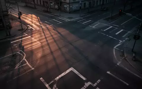 Eine leere, dunkle Straßenkreuzung in der Dämmerung mit langen Schatten und geometrischen Bodenmarkierungen. - Foto: über boerse-global.de