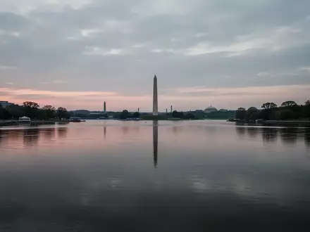 Ein ruhiger Flussabschnitt bei Dämmerung mit dem Washington Monument in der fernen Silhouette unter einem bewölkten Himmel. - Foto: über boerse-global.de
