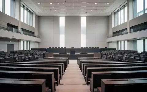 Leerer Plenarsaal des Deutschen Bundestages mit Fokus auf die Architektur und die hölzernen Sitzreihen bei natürlichem Licht. - Foto: über boerse-global.de