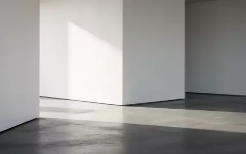 Ein minimalistischer, moderner Innenraum mit klaren Linien, poliertem Betonboden und weichem Tageslicht, das lange Schatten wirft. - Foto: über boerse-global.de