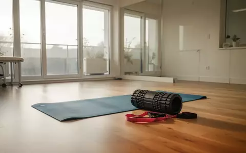Ein heller, minimalistischer Physiotherapieraum mit einer Gymnastikmatte, einer Faszienrolle und einem Widerstandsband auf dem Boden. - Foto: über boerse-global.de