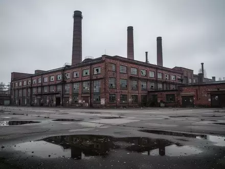 Ein großes, älteres Fabrikgebäude mit hohen Schornsteinen unter einem bedeckten Himmel, das eine industrielle Industrieanlage darstellt. - Foto: über boerse-global.de