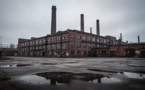 Ein großes, älteres Fabrikgebäude mit hohen Schornsteinen unter einem bedeckten Himmel, das eine industrielle Industrieanlage darstellt. - Foto: über boerse-global.de