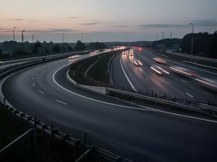 Eine leere Autobahnauffahrt in der Dämmerung mit Leitplanken und asphaltierter Fahrbahn. - Foto: über boerse-global.de