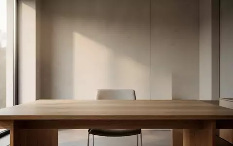 Ein minimalistischer, moderner Arbeitsplatz mit einem leeren Holztisch in einem hellen Raum bei natürlichem Tageslicht. - Foto: über boerse-global.de