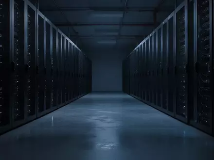 Dunkler, moderner Serverraum mit inaktiven Serverschränken in einem Flur bei schwacher blauer Beleuchtung. - Foto: über boerse-global.de