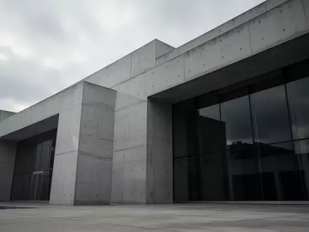 Ein minimalistisches, modernes Regierungsgebäude aus Beton unter einem bewölkten Himmel ohne sichtbare Schriftzüge. - Foto: über boerse-global.de