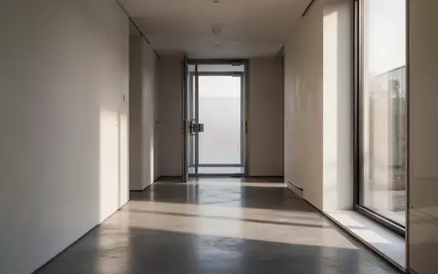 Ein minimalistischer, leerer Flur mit poliertem Betonboden und weichem Lichteinfall, der eine ruhige und sichere Atmosphäre vermittelt. - Foto: über boerse-global.de