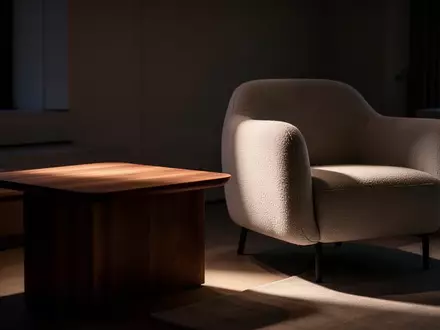 Ein minimalistisch eingerichtetes Wohnzimmer bei Dämmerung mit einem leeren Beistelltisch neben einem Sessel. - Foto: über boerse-global.de