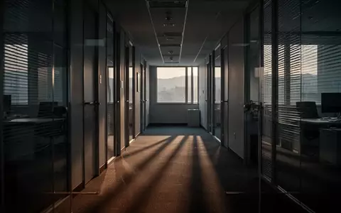 Ein leerer, in DĂ€mmerlicht getauchter BĂŒroflur mit langen Schatten, der die AtmosphĂ€re zum Ende der Arbeitswoche einfĂ€ngt. - Foto: ĂŒber boerse-global.de
