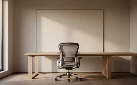 Ein minimalistischer Arbeitsplatz mit einem leeren ergonomischen Stuhl vor einer schlichten Wand bei natürlichem Licht. - Foto: über boerse-global.de