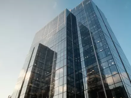 Moderne Glasfassade eines Wolkenkratzers vor blauem Himmel. - Foto: über boerse-global.de