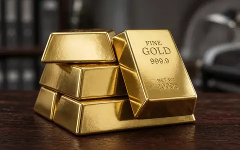 Mehrere glänzende Goldbarren auf einem dunklen Holztisch in einer professionellen Umgebung. - Foto: über boerse-global.de