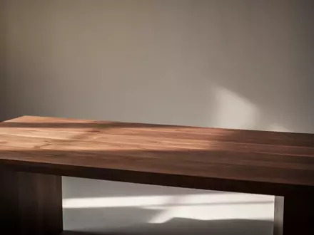 Ein minimalistischer, professioneller Arbeitsplatz in einem Studio mit warmem, natürlichem Licht und einem Schreibtisch aus dunklem Walnussholz. - Foto: über boerse-global.de