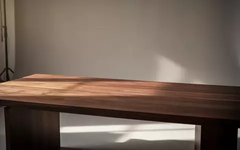 Ein minimalistischer, professioneller Arbeitsplatz in einem Studio mit warmem, natürlichem Licht und einem Schreibtisch aus dunklem Walnussholz. - Foto: über boerse-global.de