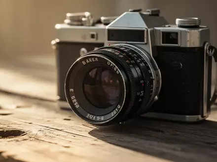 Eine Nahaufnahme eines alten 35mm-Kameraobjektivs auf einer hölzernen Oberfläche bei natürlichem Tageslicht. - Foto: über boerse-global.de