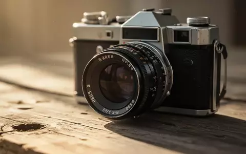 Eine Nahaufnahme eines alten 35mm-Kameraobjektivs auf einer hölzernen Oberfläche bei natürlichem Tageslicht. - Foto: über boerse-global.de