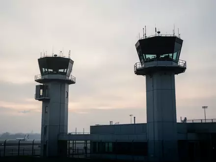 Silhouette eines modernen Flughafenkontrollturms vor einem bewölkten Morgenhimmel. - Foto: über boerse-global.de