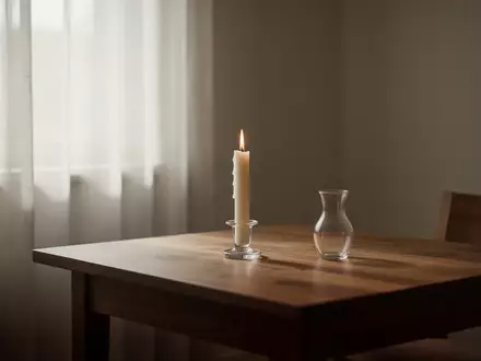 Ein minimalistisch eingerichteter Raum mit weichem Tageslicht, einer einzelnen Kerze und einer leeren Glasvase auf einem Holztisch. - Foto: über boerse-global.de