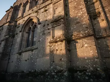 Detailaufnahme einer historischen Kirchenmauer aus Naturstein mit sichtbaren Witterungsspuren und architektonischen Strukturen. - Foto: über boerse-global.de