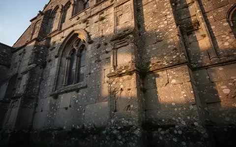 Detailaufnahme einer historischen Kirchenmauer aus Naturstein mit sichtbaren Witterungsspuren und architektonischen Strukturen. - Foto: über boerse-global.de