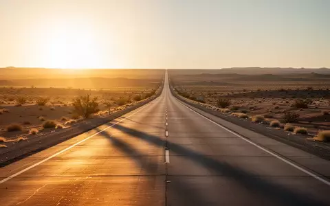 Eine weitläufige, leere Autobahn in einer sonnendurchfluteten Wüstenlandschaft während der goldenen Stunde. - Foto: über boerse-global.de