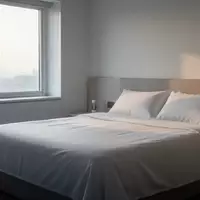 Ein minimalistisches Schlafzimmer mit weichem Tageslicht, das auf ein unbenutztes, ordentlich bezogenes Bett fällt. - Foto: über boerse-global.de
