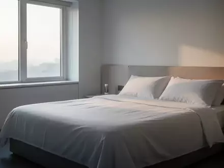 Ein minimalistisches Schlafzimmer mit weichem Tageslicht, das auf ein unbenutztes, ordentlich bezogenes Bett fällt. - Foto: über boerse-global.de