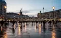 Ein belebter Berliner Stadtplatz in der Dämmerung mit architektonischen Strukturen und Straßenbeleuchtung. - Foto: über boerse-global.de