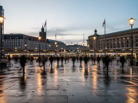 Ein belebter Berliner Stadtplatz in der Dämmerung mit architektonischen Strukturen und Straßenbeleuchtung. - Foto: über boerse-global.de