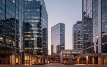 Moderne Glasfassaden eines Finanzviertels bei Dämmerung, die wirtschaftliche Dynamik und urbane Architektur symbolisieren. - Foto: über boerse-global.de