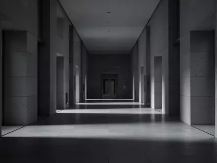 Ein leerer, minimalistischer Flur in einem modernen Gerichtsgebäude mit langen Schatten auf dem Boden. - Foto: über boerse-global.de