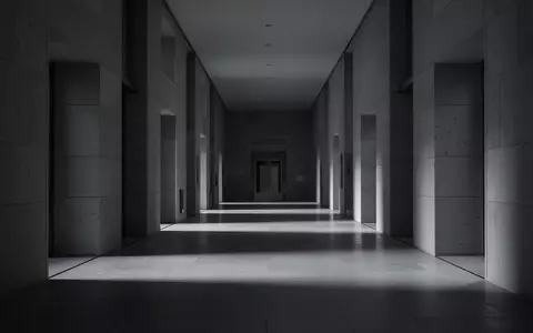 Ein leerer, minimalistischer Flur in einem modernen Gerichtsgebäude mit langen Schatten auf dem Boden. - Foto: über boerse-global.de