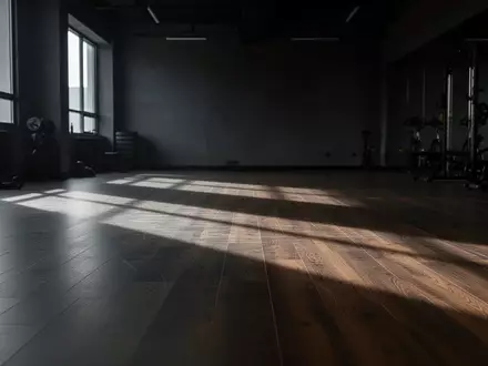 Ein minimalistischer, leerer Fitnessraum mit hellem Holzboden und weichem Lichteinfall. - Foto: über boerse-global.de