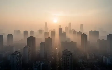 Dichte, dunstige Stadtlandschaft bei Sonnenaufgang, die auf Luftverschmutzung und die Belastung der Atemwege hinweist. - Foto: über boerse-global.de
